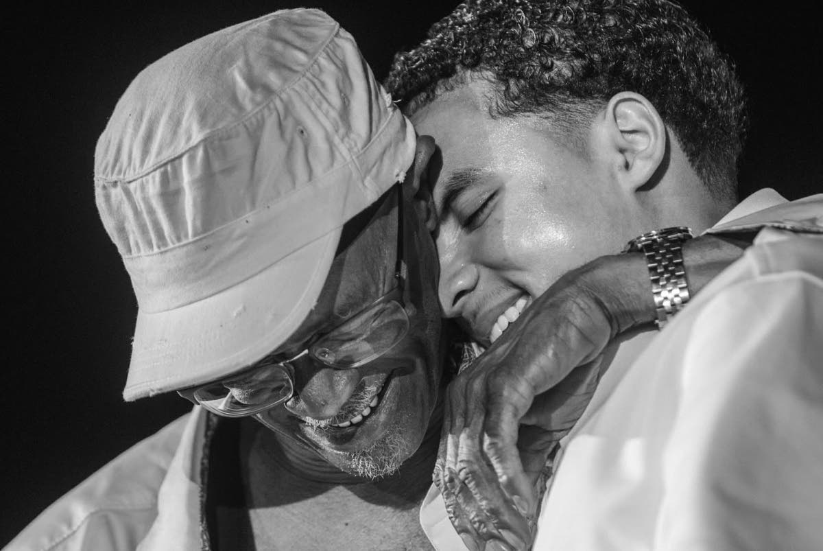 Beres Hammond embraces his grandson, Kingston Pauyo (right), on stage during the All White night on the Love and Harmony Cruise.