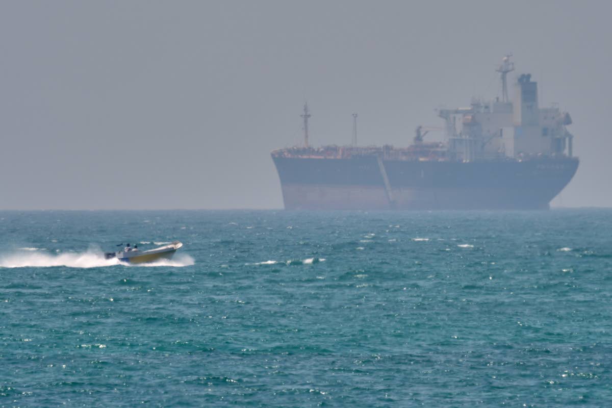In this file photo, a boat sails past a tanker anchored on the Strait of Hormuz off the coast Qeshm island, Iran, on April 18, 2026. 