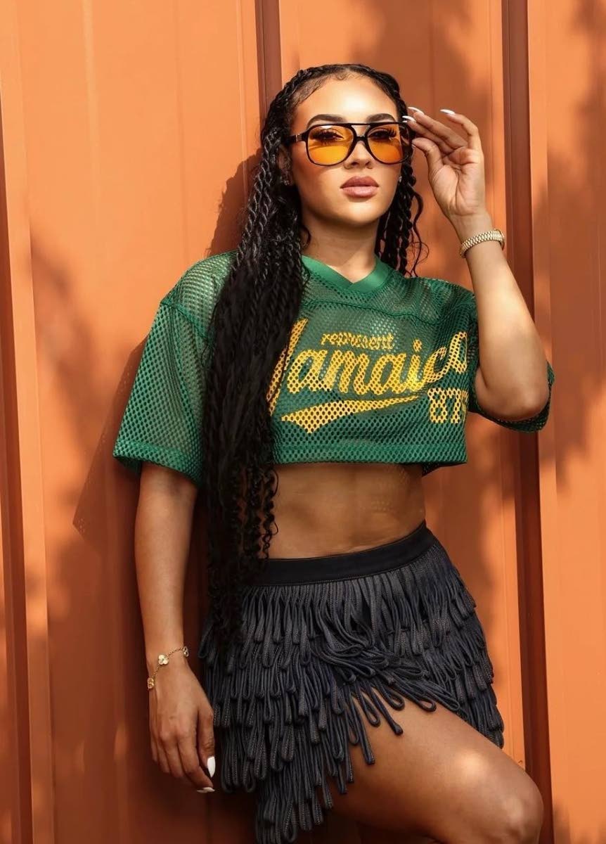Professional makeup artist Chynnel Isaacs adds playful contrast to the Green Represent Jamaica Mesh Crop Top, paired with a fringe mini skirt.