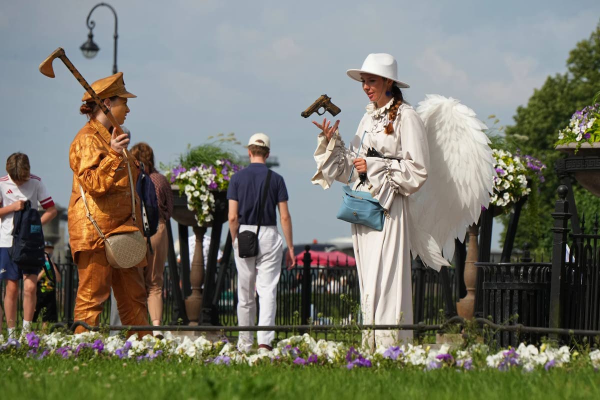 A street performer wearing an angel costume plays with a toy gun in central St. Petersburg, Russia, Wednesday, July 15, 2026. 