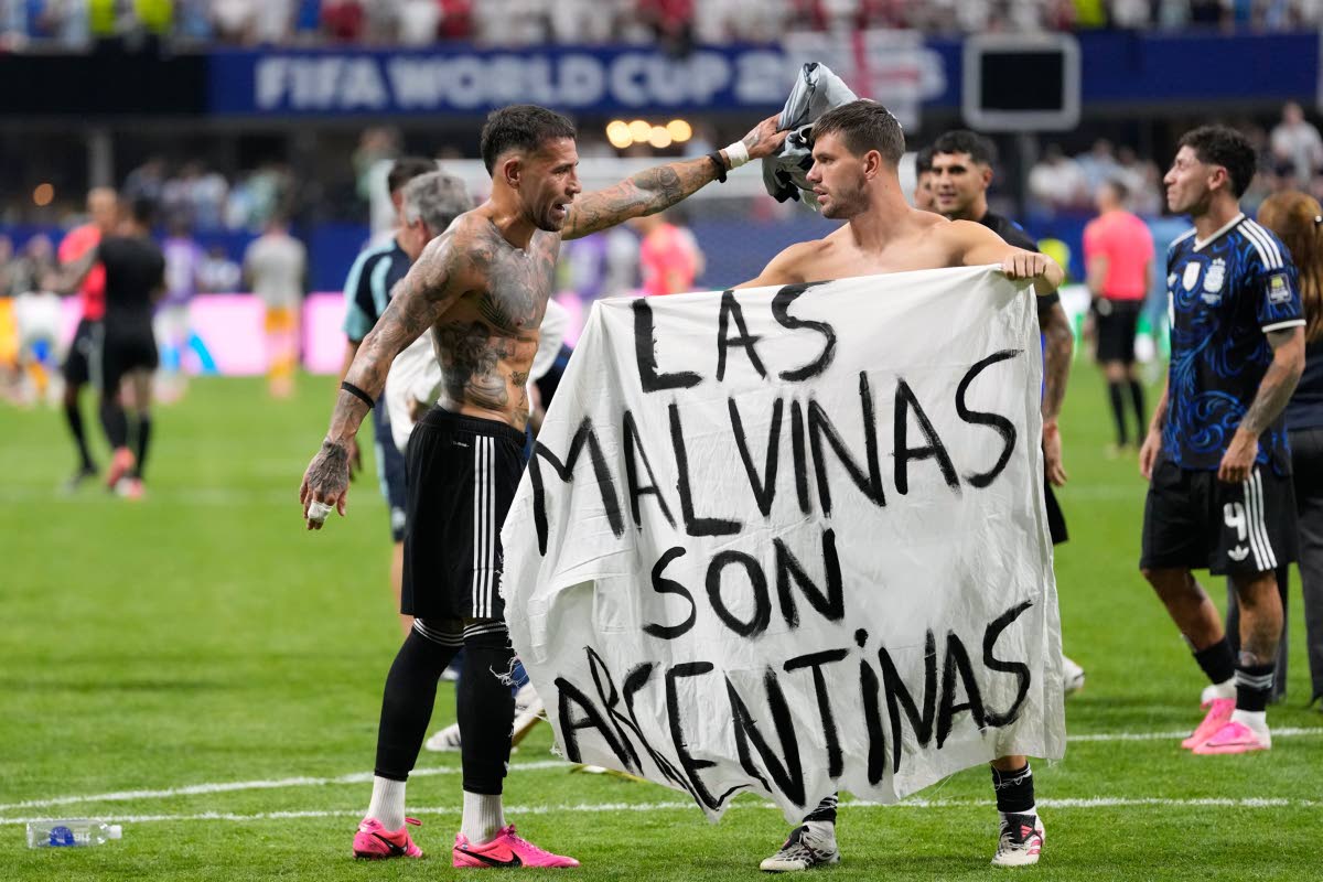Argentina's Giovani Lo Celso holds a banner with the words "The Malvinas are Argentine", referring to the Falkland Islands, while teammate Argentina's Nicolas Otamendi gestures to him, at the end of the World Cup semifinal soccer match between England and 