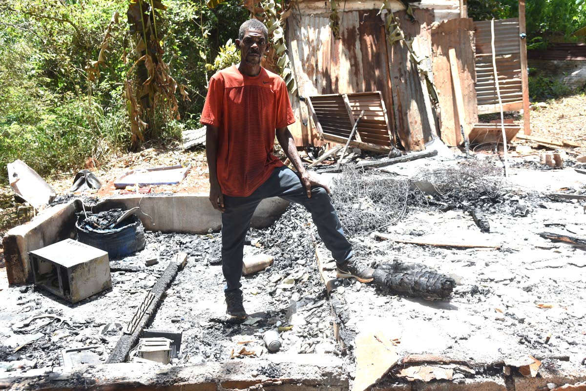 Robert Douglas stands amid the ruins of his home, which was destroyed in a suspected arson attack on Tuesday.