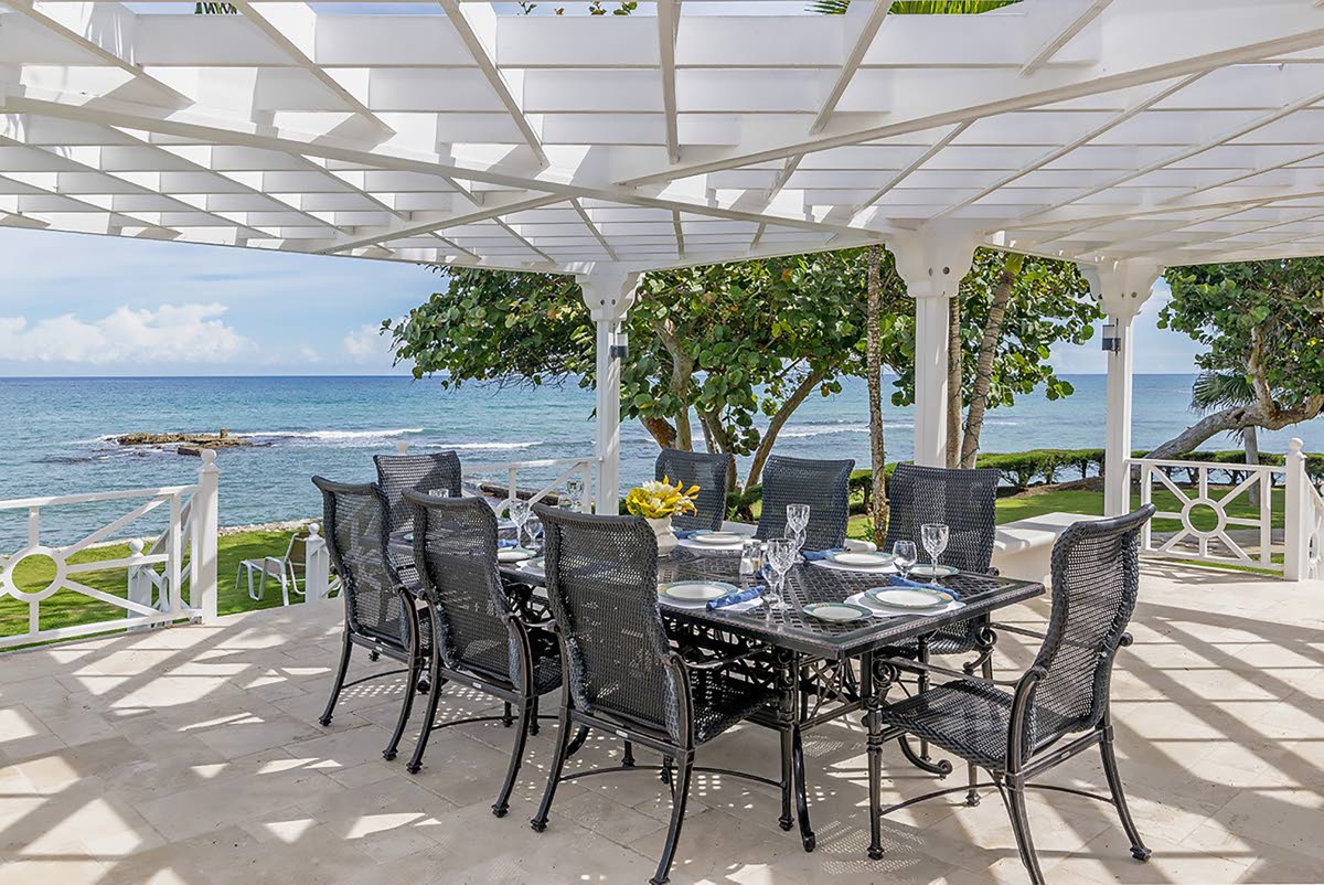 An open-air, trellised seafront dining terrace. 