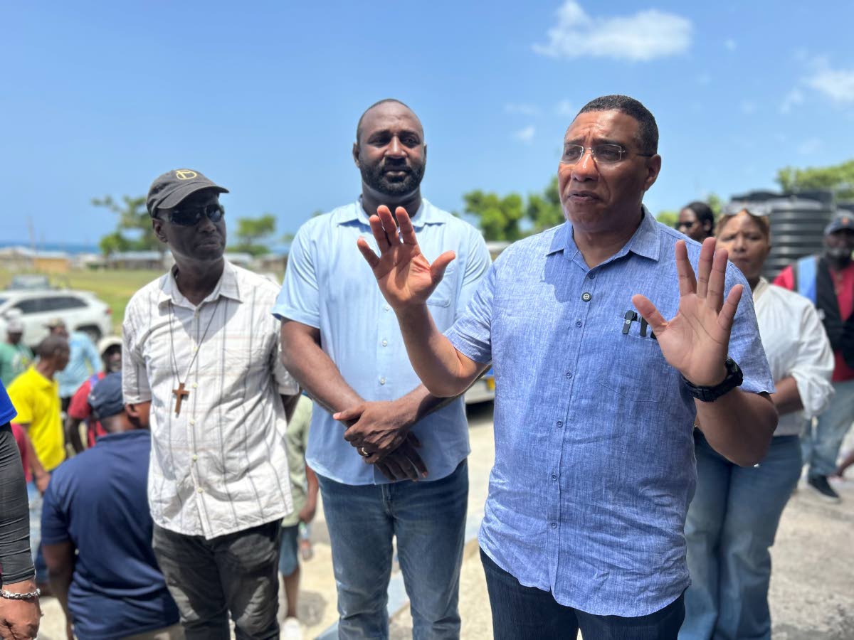 Prime Minister Dr Andrew Holness (right) addresses residents in Whitehouse last Friday as Councillor Michael Jackson (left) and Westmoreland Eastern Member of Parliament Dr Dayton Campbell look on.
