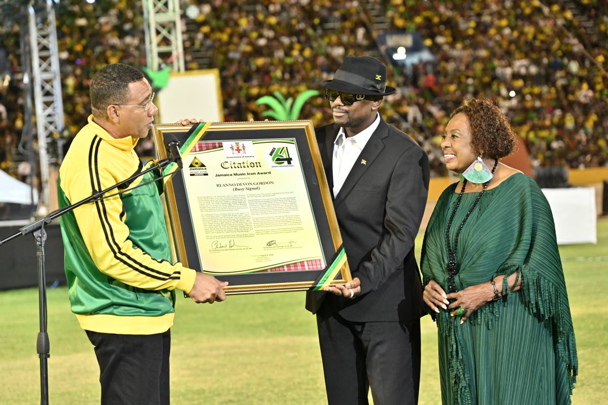 Dancehall artiste Busy Signal (centre) accepts the Reggae Icon Award from Prime Minister Holness as Minister Grange looks on. 