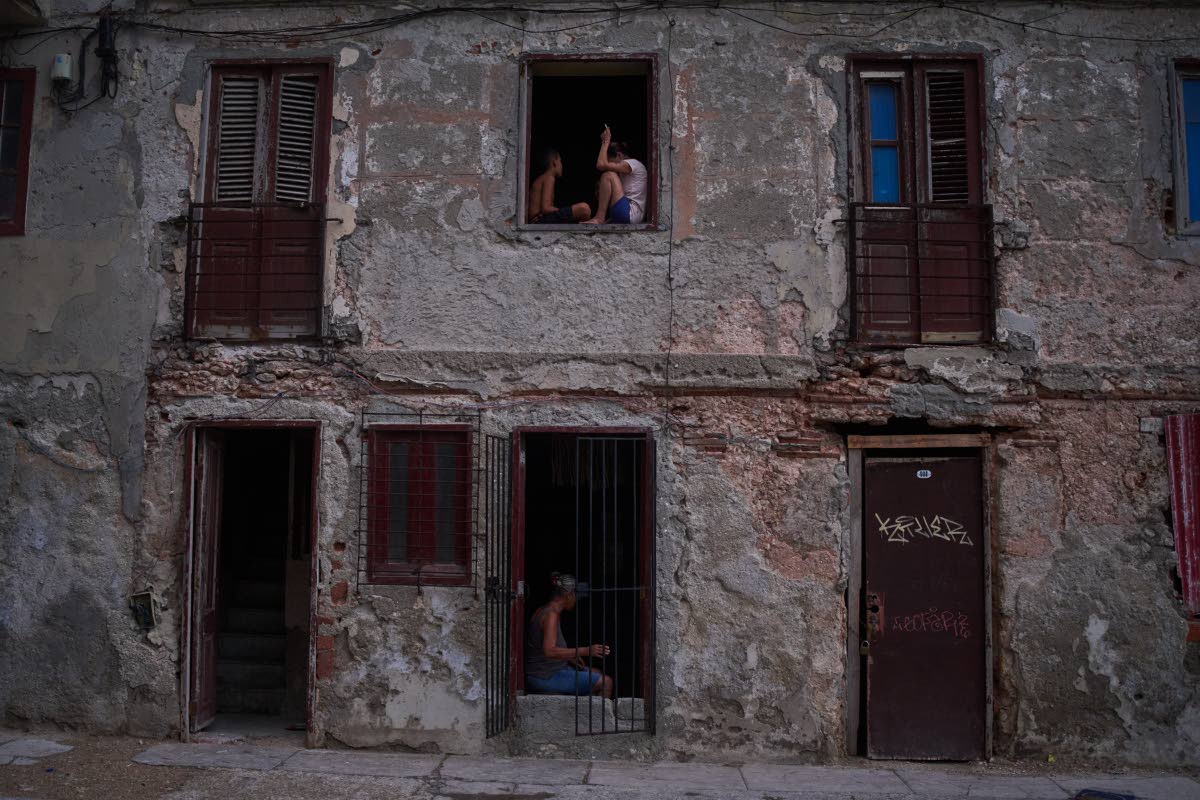 People catch the cool air from the street at their home’s window during a blackout in Havana, Cuba, in July.