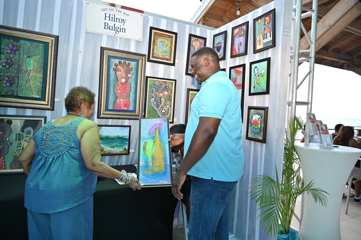 Artist and organiser Hilroy Bulgin completes a sale during the Art on the Bay exhibition at Pier 1 in Montego Bay.