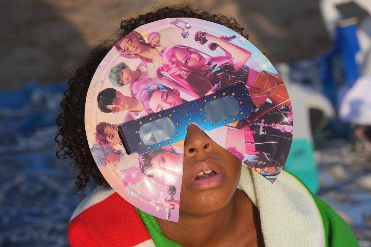 A beachgoer wearing special eclipse glasses looks up during the beginning phase of a solar eclipse at Puerto de Sagunto beach near Valencia, Spain, Wednesday.