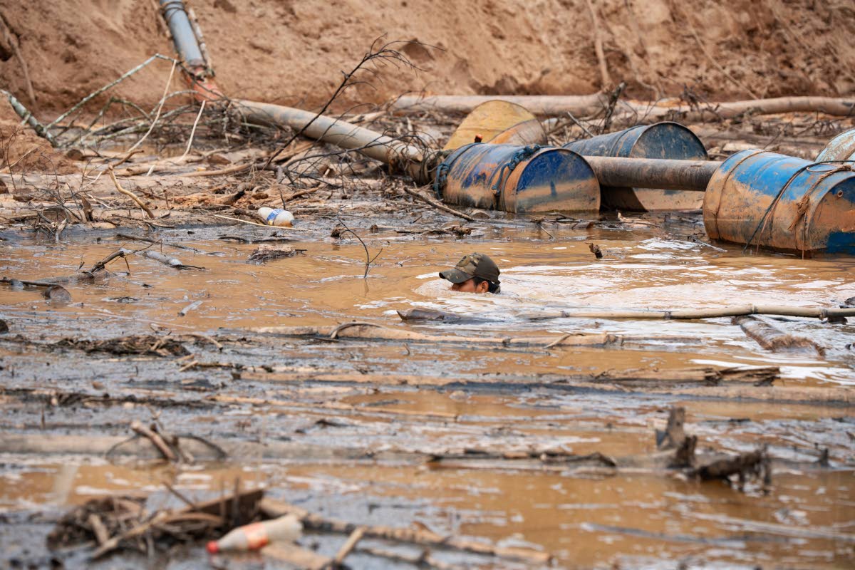 A Peruvian Navy soldier swims in a human-made pool to extract gold using chemical products during an operation to combat illegal mining in the Tambopata National Reserve.
