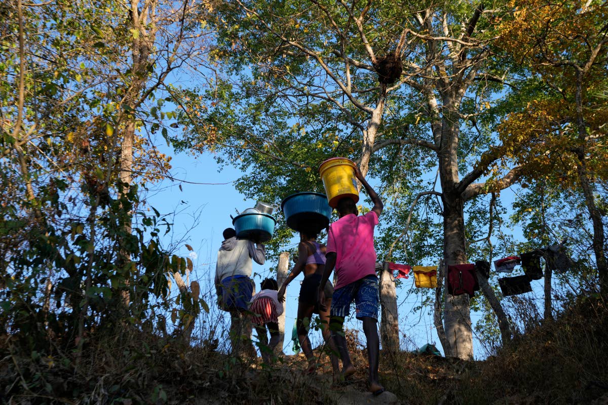 Children carry water from the Branco River at dawn at the Kalunga quilombo, a Brazilian settlement founded by escaped enslaved Africans, in the rural area of Cavalcante in Goias state, Brazil, August 15, 2022.