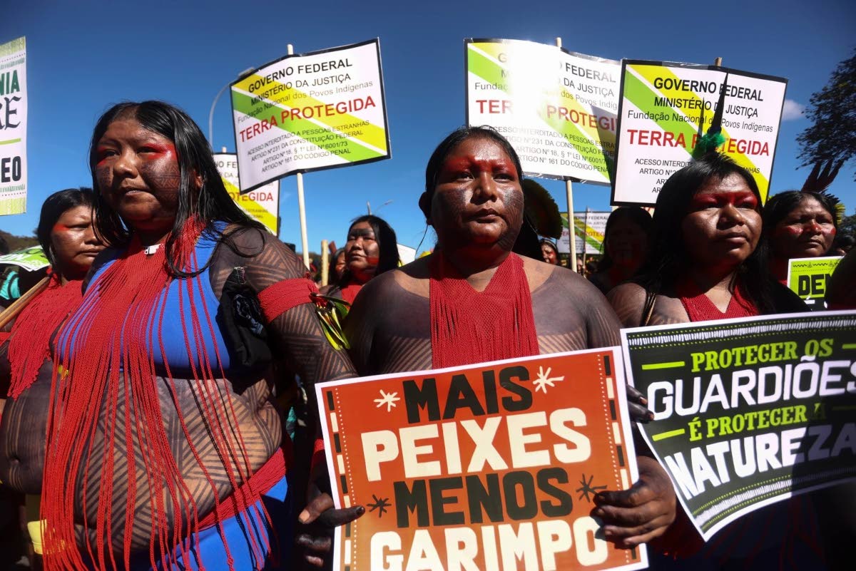 An Indigenous woman marches with a sign that reads in Portuguese “More fish, less mining”, during the 20th annual Free Land Indigenous Camp in Brasilia, Brazil, April 23, 2024.
