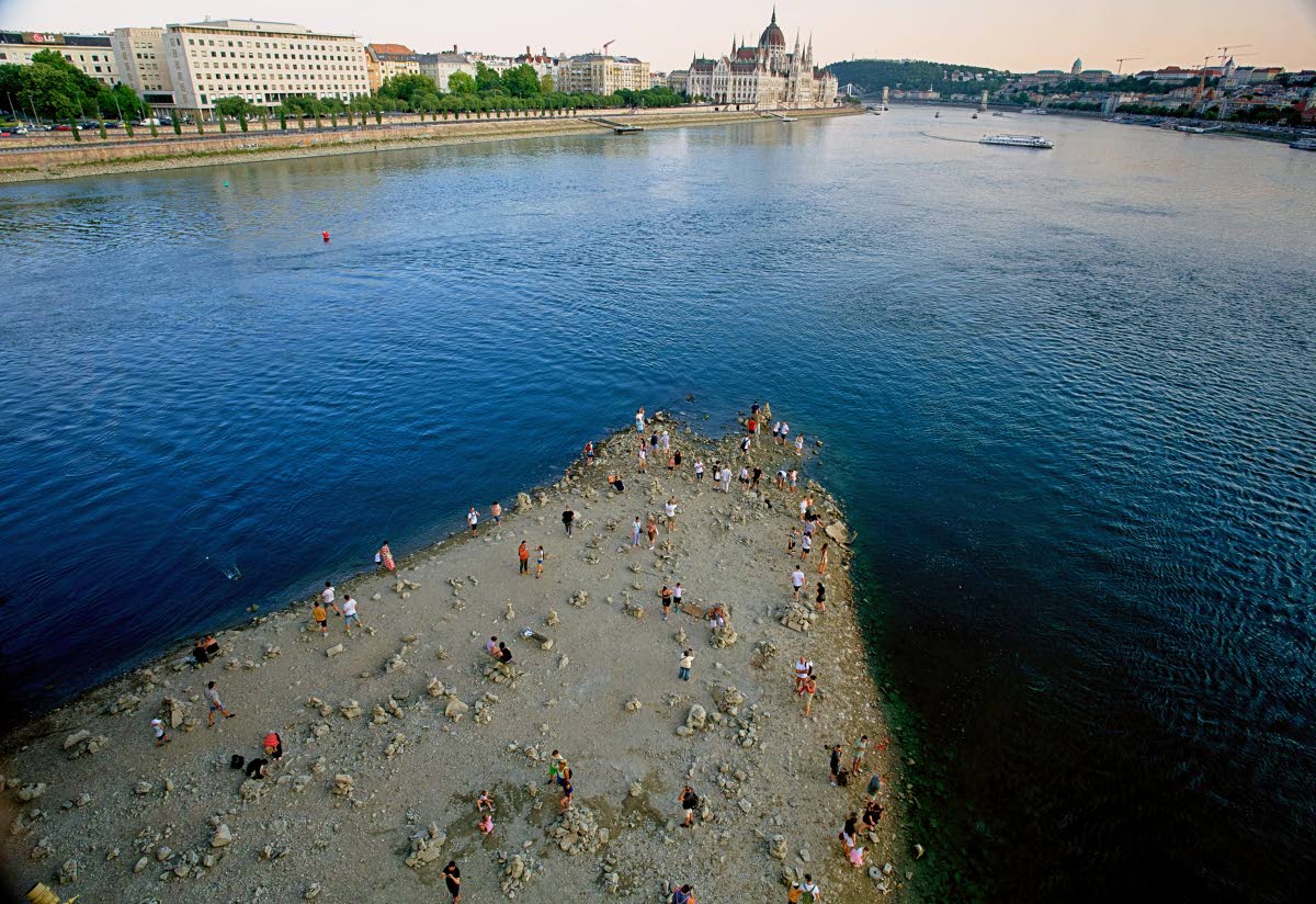 People walk on a sandbar underneath the Danube’s Margareth Bridge in downtown Budapest, Hungary, on August 5, 2026, as the river, which runs through 10 European countries, has receded never-before-seen low water levels.
