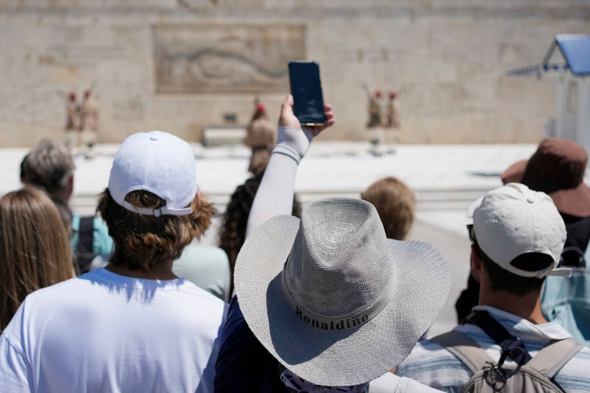 Tourists wearing hats visit the Tomb of the Unknown Soldier outside the Greek Parliament in Athens, Greece.