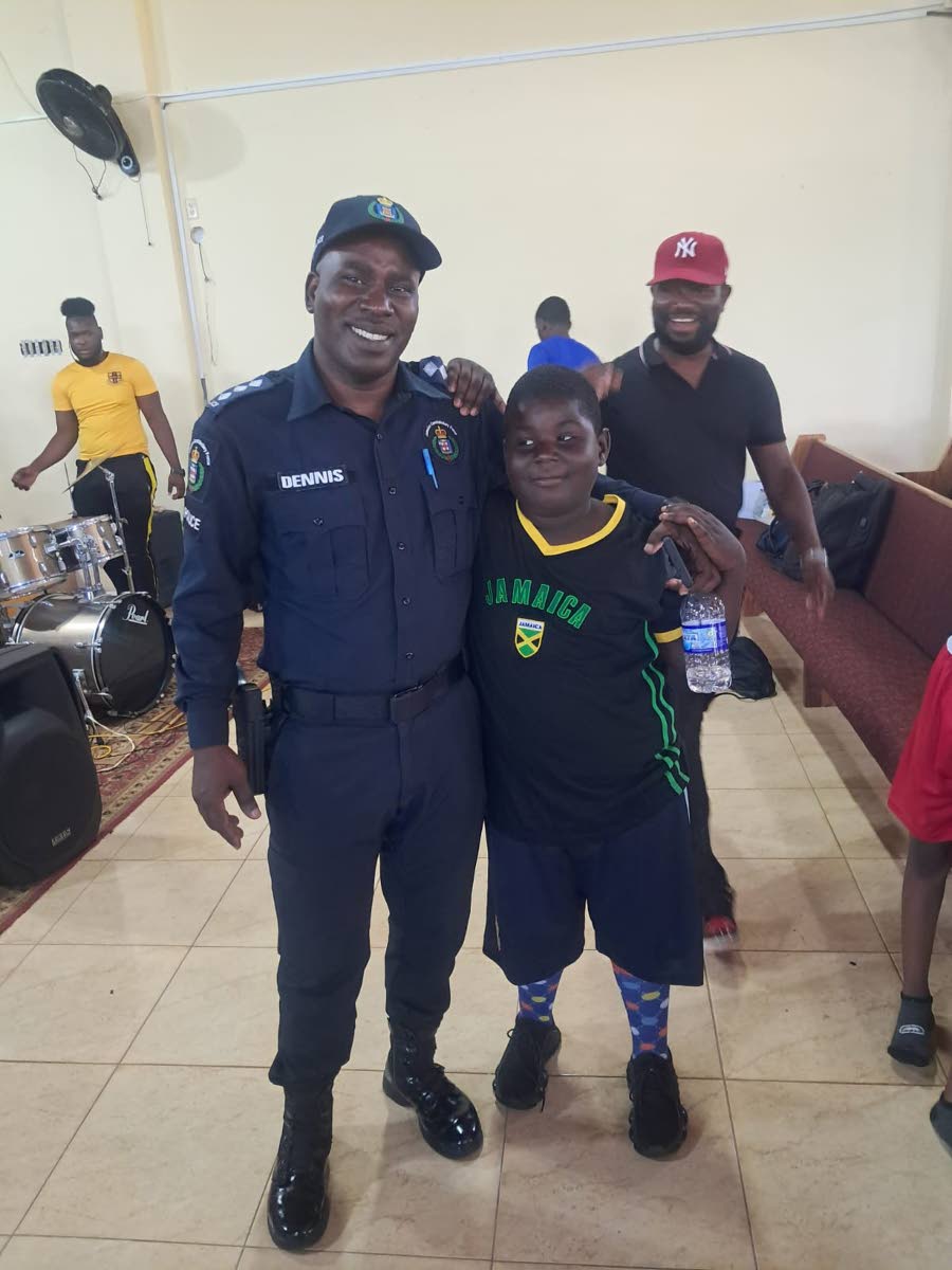 Superintendent Odaine Dennis, commanding officer for the Manchester Division, greets and poses with a young camper last week.
