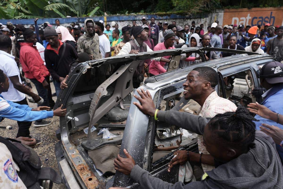 Residents try to flip over a car to block a street as they protest for police intervention after deadly gang attacks in the Kenscoff neighbourhood of Port-au-Prince, Haiti, earlier this week.