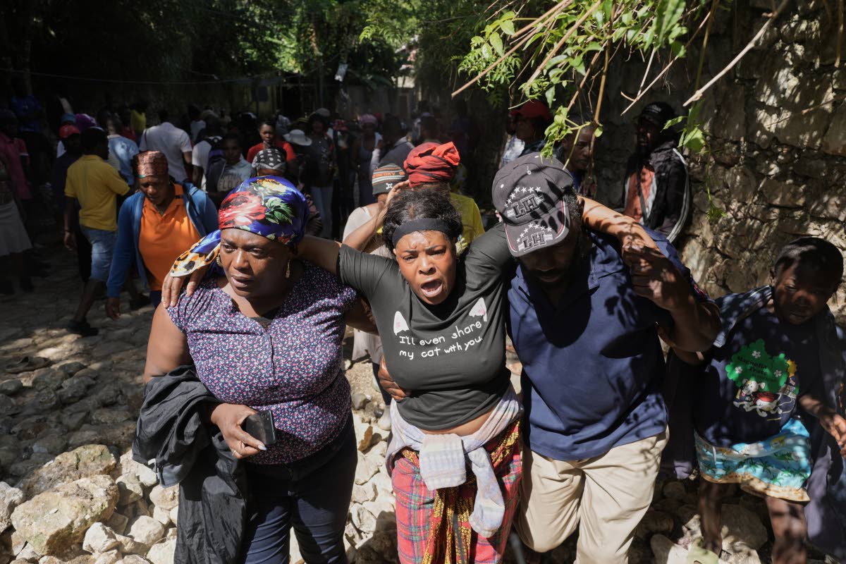 People watch as the bodies of their relatives who were killed in a gang attack are carried away by morgue workers in the Kenscoff neighbourhood of Port-au-Prince, Haiti, on Monday.