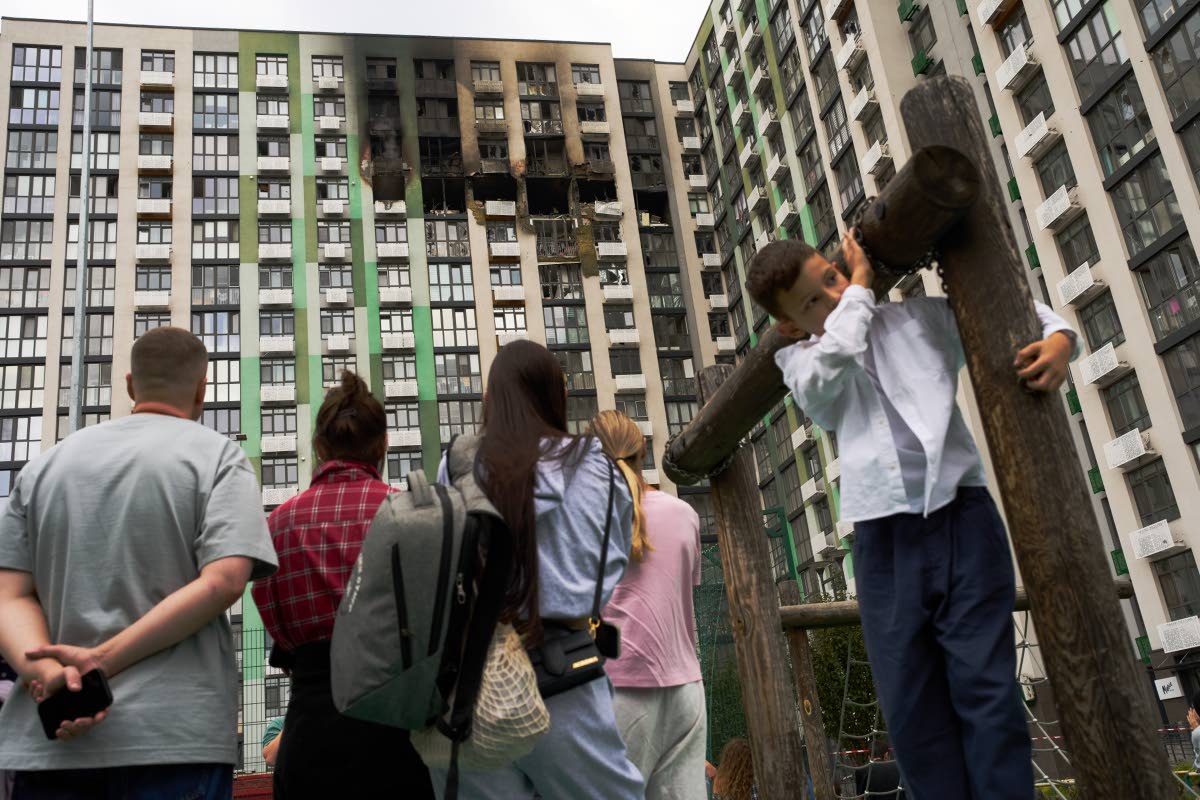 Locals watch as firefighters work after a Russian drone attack struck a residential building in Kyiv, Tuesday, Sept. 1, 2026.