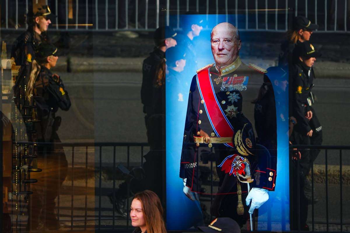 Police officers reflected in a window with a display showing Norway’s late King Harald V prior to his funeral in Oslo, Wednesday. 