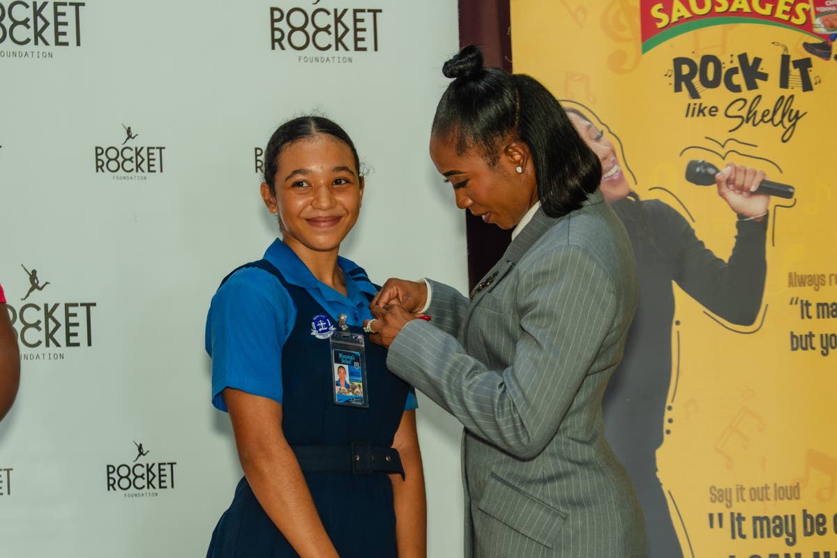  Shelly-Ann Fraser-Pryce, founder and chairwoman of the Pocket Rocket Foundation, pins 2026 scholar Jazmyne Wilkinson during the foundation’s annual scholarship awards at the Wolmer’s Girls’ School Hall on Thursday, September 24.