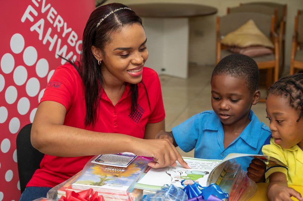 Project STAR Community Services Coordinator Jodi-Ann Bowen (left) reads with young recipients as they explore books received through the Supplies4Students initiative.
