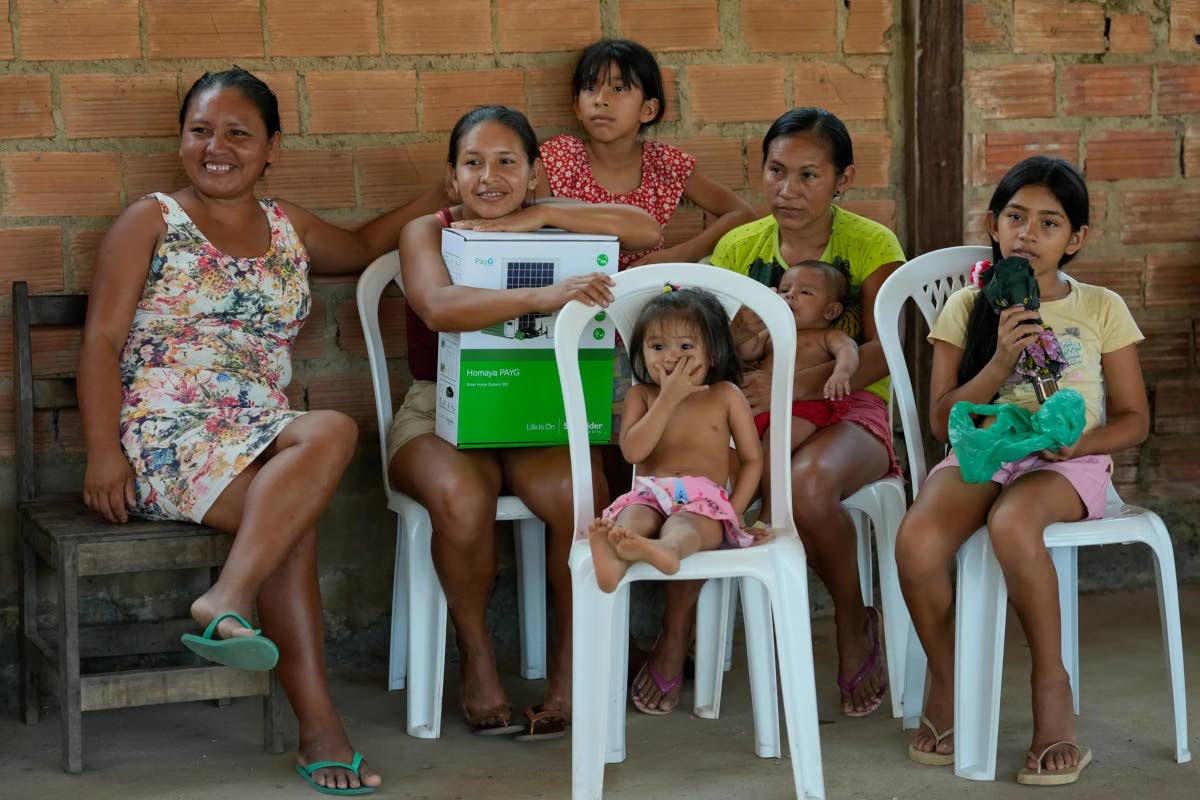 Daiana Arapiuns, who is part of the Arapium Indigenous group, sits with relatives holding a box containing a donated solar-power system in the Nova Sociedade community near Santarem, Para state, Brazil, September 3.