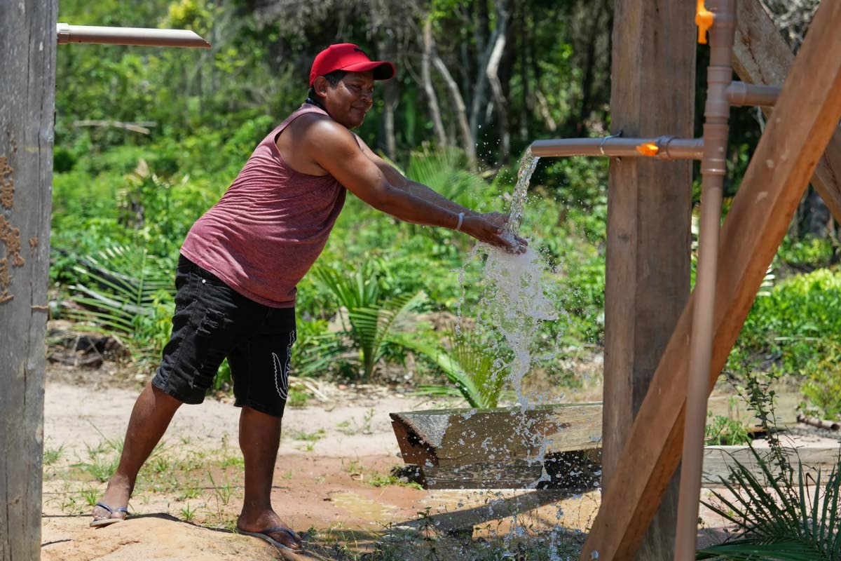 Arapium Indigenous leader Tiago Silva cools off with water pumped from a well using a solar-powered system in the Nova Sociedade community near Santarem, Para state, Brazil.