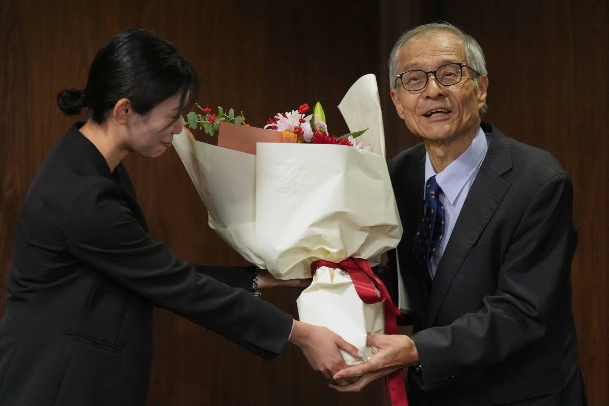 Japanese chemist Kenso Soai receives a bouquet of flowers from a university staff member before the press conference at Tokyo University of Science in Tokyo, Wednesday, after winning the Nobel Prize in chemistry. 