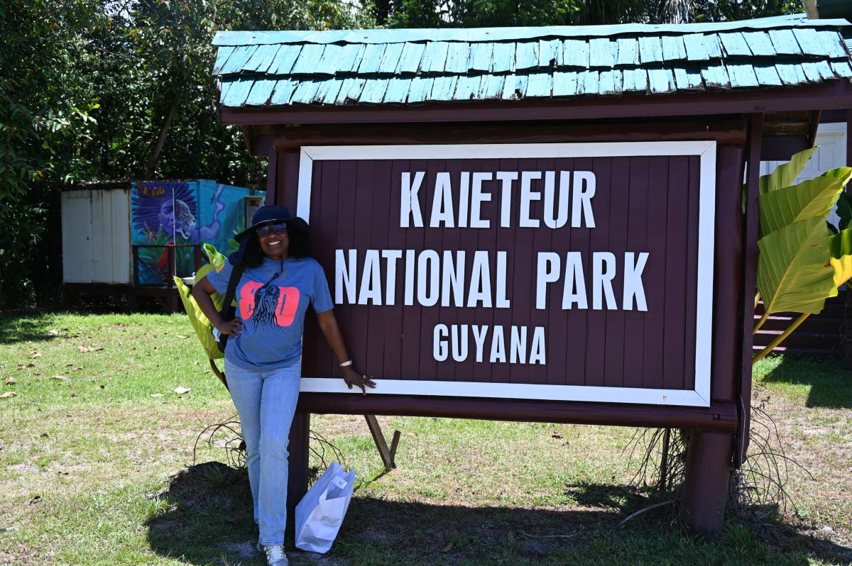Journalist Janet Silvera poses at the official sign at the Kaieteur National Park in Guyana.