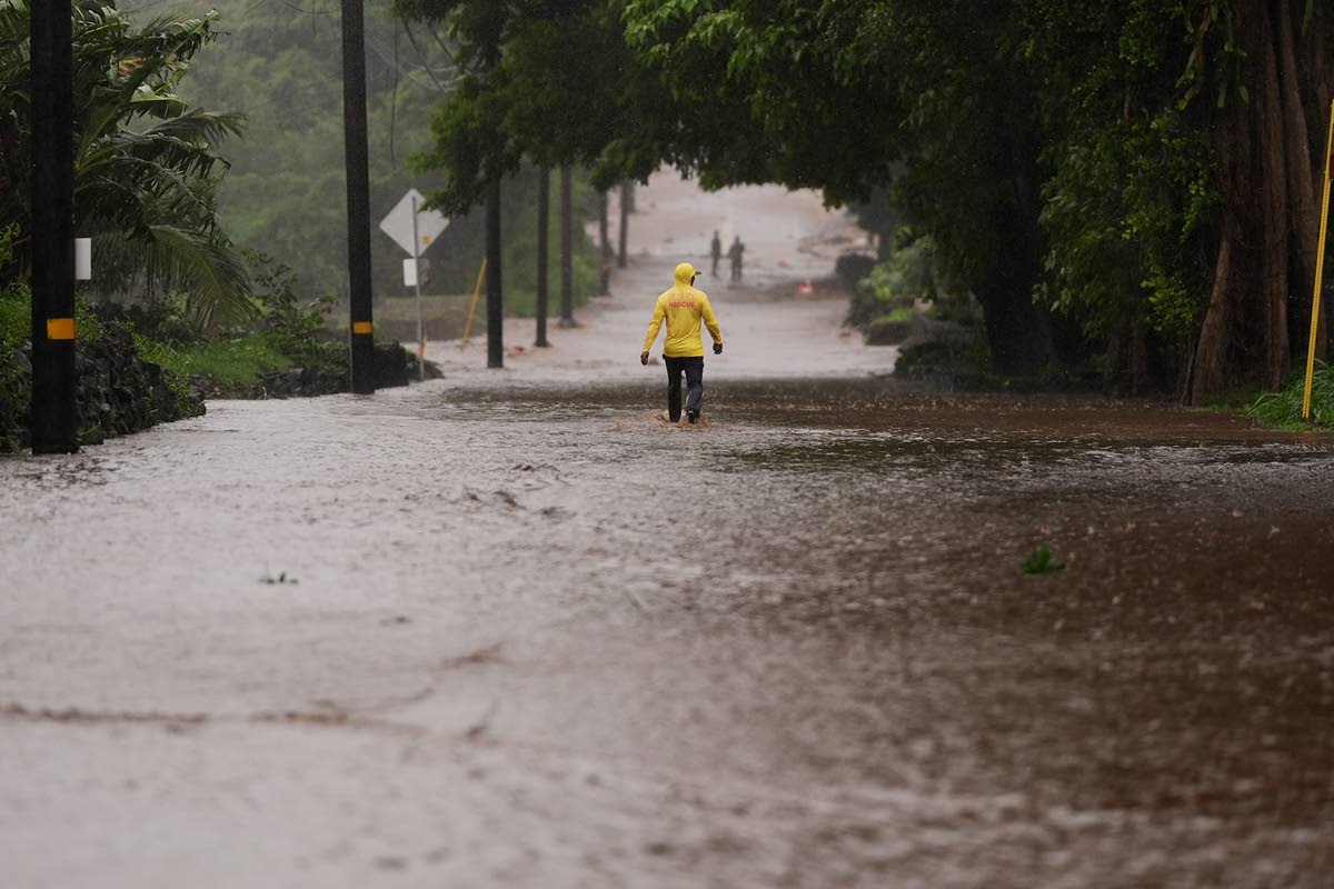 Fire Captain Lui Sales of the Hawaii Fire Department looks for residents to help as rainwater from nearby Hurricane Nolo flood a section of Mamalahoa highway September 26, near Naalehu, Hawaii. 