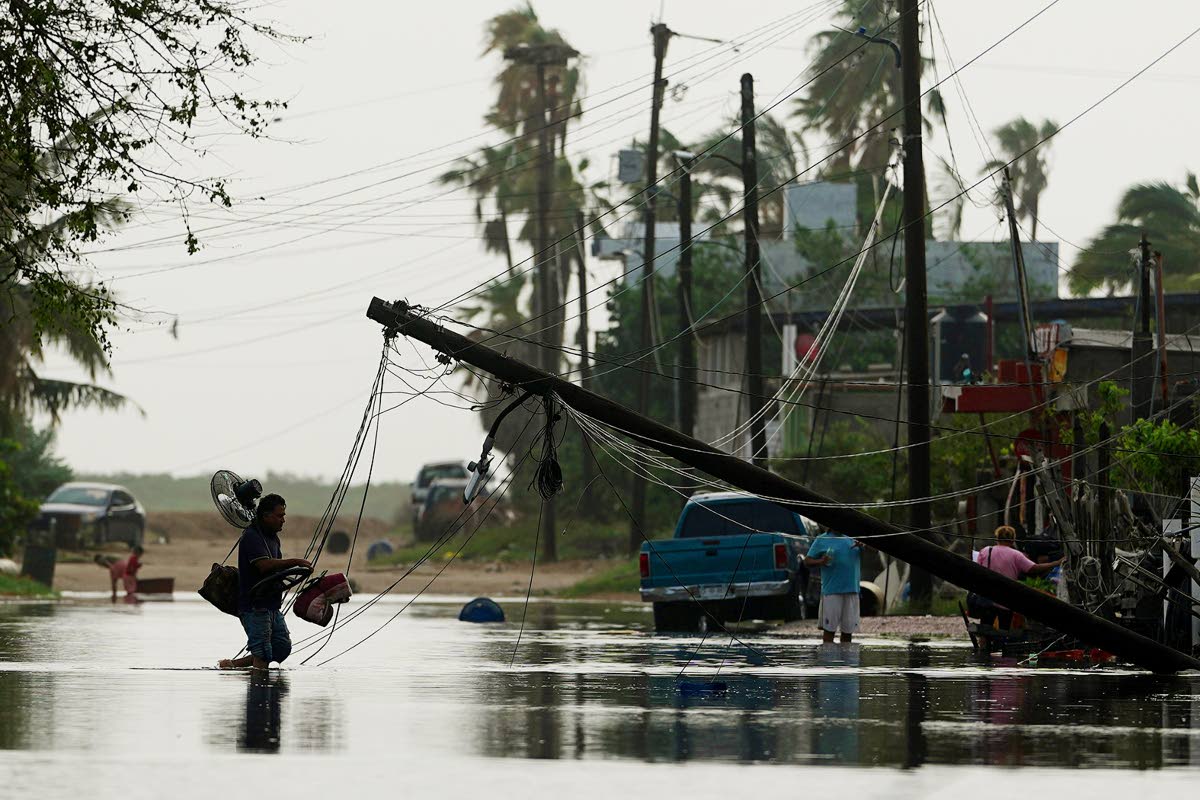 A man carries items through floodwater past downed electric lines after the passing of Hurricane Polo in Puerto San Carlos, Baja California Sur state, Mexico, September 29.