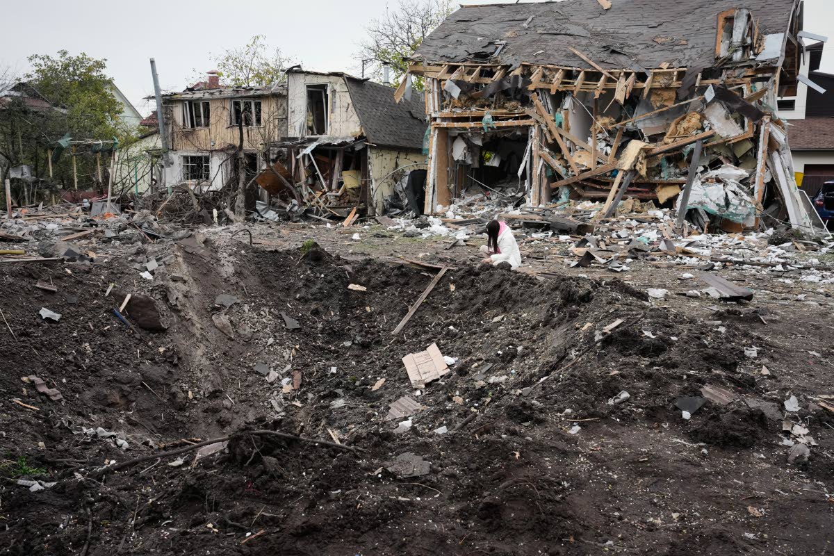 A woman looks at a crater after a Russian missile strike in Kyiv, Ukraine.