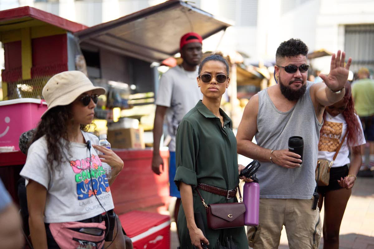 Director Storm Saulter (right) preps a scene for the thriller limited series, ‘Possession’ on Water Lane, in downtown Kingston, with his lead actress Gugu Mbatha-Raw (centre) as key cast production assistant Didi Beck looks on. 