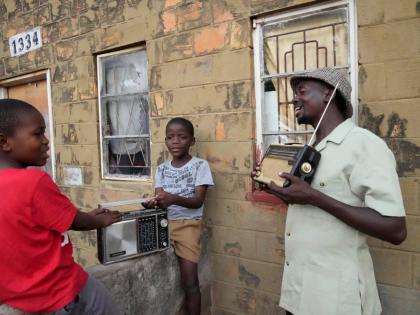 Ngwiza Khumbulani Moyo, a vintage collector, shows a young boy some of his old radio sets outside his home in Bulawayo.