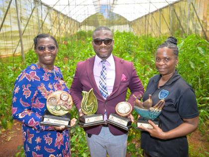 Principal of the Manchester-based Bethabara Primary School, Cecil Hamilton (centre), along with Vice Principal Ritta Evans Lowe (left), and teacher, Dionne Salkey Francis, display trophies won by the school for its high-quality greenhouse crops and value