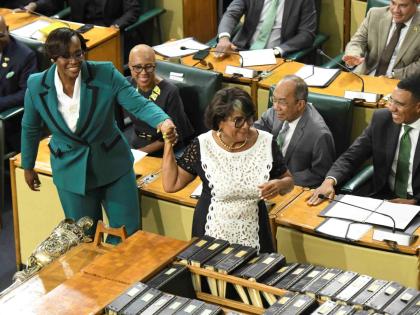 Newly elected House Speaker Juliet Holness (left) feigns reluctance as Former House Speaker Marisa Dalrymple-Philibert ‘drags’ her to the chair to take the oath of office during the swearing-in ceremony for members of the Upper and Lower Houses of Parl