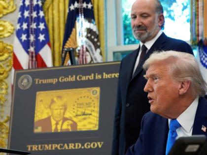 US President Donald Trump speaks as Commerce Secretary Howard Lutnick listens alongside a poster of the Trump Gold Card in the Oval Office of the White House, on Friday, September 19, in Washington. 