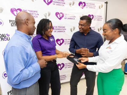 Serika Sterling (second left), founder and chairwoman, Preemie Foundation of Jamaica, shows a premature baby bib made in honour of premature babies fighting for life to (from left) Dr Wayne Palmer, president, The Jamaica Cycling Federation; Courtney Cephas