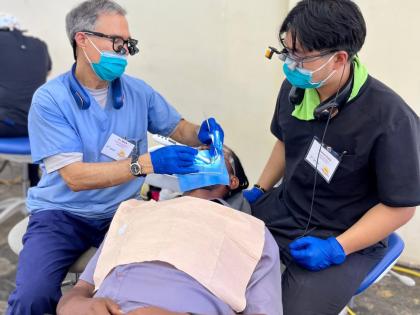 Dr Mark Stevenson (left), a dental practitioner with 34 years of experience, performs a root canal on a faculty member at William Knibb Memorial High School as part of the Great Shape! Inc. 1000 Smiles Mission, hosted at the school. Assisting him is Daniel