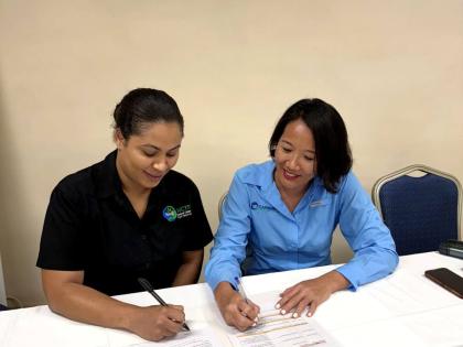 Danellia Aitcheson (left), manager of the National Conservation Trust Fund of Jamaica, and Tanja Lieuw, Conservation Finance Programme Manager at the Caribbean Biodiversity Fund, affix their signatures to the partnership document.