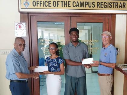 Radley Reid (left) and Donald Patterson (right), directors of the Rotary Club of St Andrew North Education Foundation, present education grants to Lilly Anne Douglas and Victor Stewart of The University of the West Indies. The recipients were two of four s