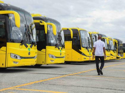 A man walks by a line of JUTC buses at the JUTC Portmore Depot.