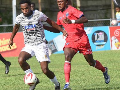 Adrian Reid (left) of  Cavalier dribbles clear of Diamond Clarke of Spanish Town Police FC during their Jamaica Premier League match at the Waterhouse Mini Stadium yesterday.