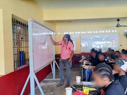 Damion Crawford, member of parliament for St Catherine North Western, goes through a math equation during one of the math classes at Charlemont High School in Linstead, St Catherine on October 18.