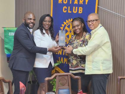 From left: Lemar James, president of the Rotary Club of Montego Bay, and Yemima Garcia, assistant governor and director of the Rotary Club of Montego Bay, present a bottle of wine to Rotarians Dr Ella Aiken and her husband, Professor William Aiken, distric