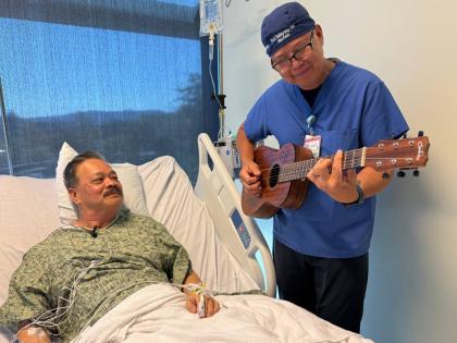 Nurse Rod Salaysay plays guitar for patient Richard Hoang in the recovery unit of UC San Diego Health in San Diego, California, on September 30, 2025. 