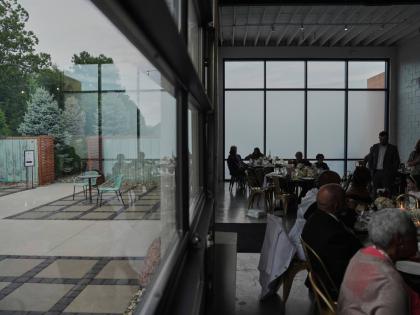 At BOTTOM: Guests sit inside during cocktail hour as empty chairs sit outside during a wedding on August 23, 2025 in Newtown, Ohio.