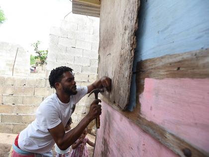 Devon Osbourne battens down a section of his house in Compound, Alligator Pond, Manchester, as he prepared for the arrival of Hurricane Melissa.