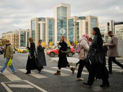 People cross a street, with Russian oil company Lukoil’s headquarters seen in the background, in Moscow, Russia, on Thursday, October, 23, 2025.