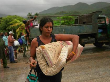 A woman carrying a mattress in the rain evacuates before the arrival of Hurricane Melissa in Cañizo, a community in Santiago de Cuba, Tuesday, October 28, 2025. (AP Photo/Ramon Espinosa)