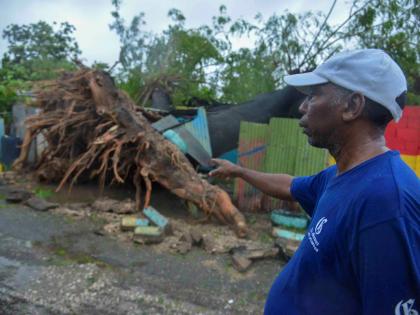 Clive Evans, a resident of Walker’s Avenue in Gregory Park, St Catherine, looks at the damage to his house caused by a fallen tree during Hurricane Melissa on Tuesday.